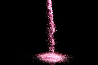 Photo of Sprinkling rose glitter on black background, bokeh effect