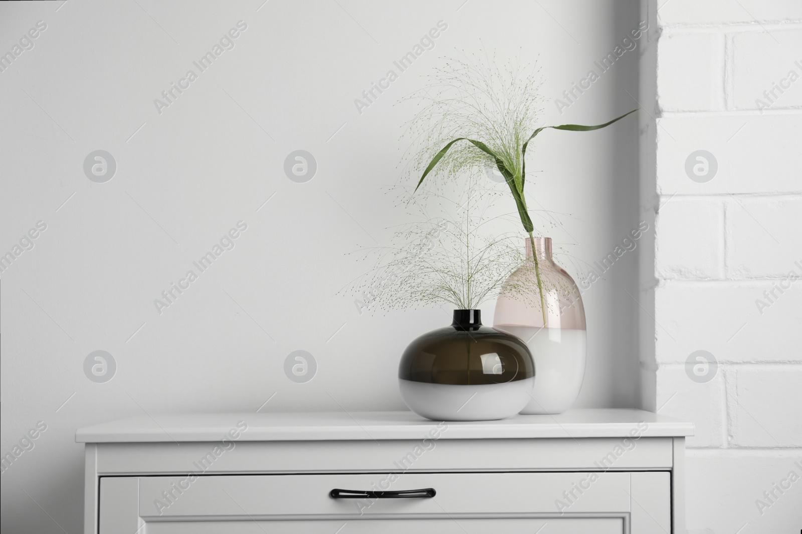 Photo of Decorative vases with plants on commode indoors