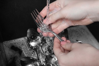 Photo of Woman washing silver kitchenware under stream of water in sink, closeup