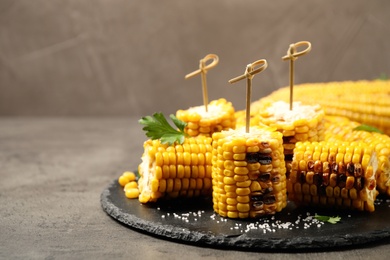 Photo of Tasty grilled corn with salt on grey table