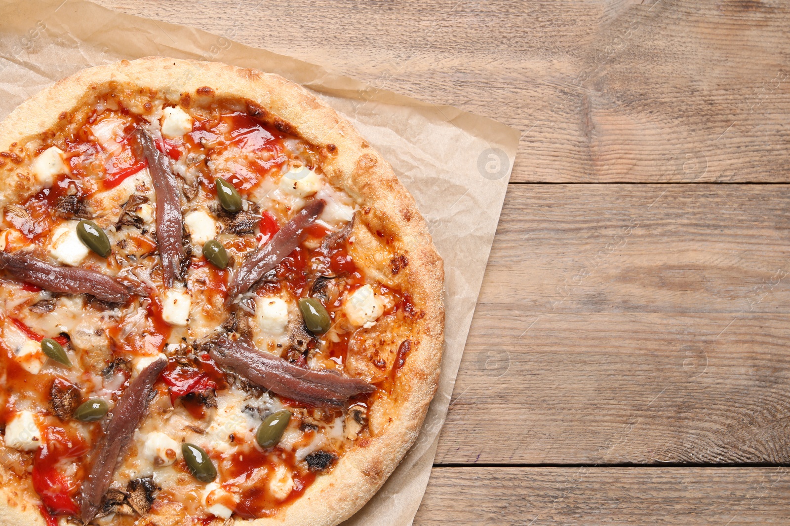 Photo of Tasty pizza with anchovies and olives on wooden table, top view. Space for text