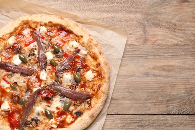 Tasty pizza with anchovies and olives on wooden table, top view. Space for text