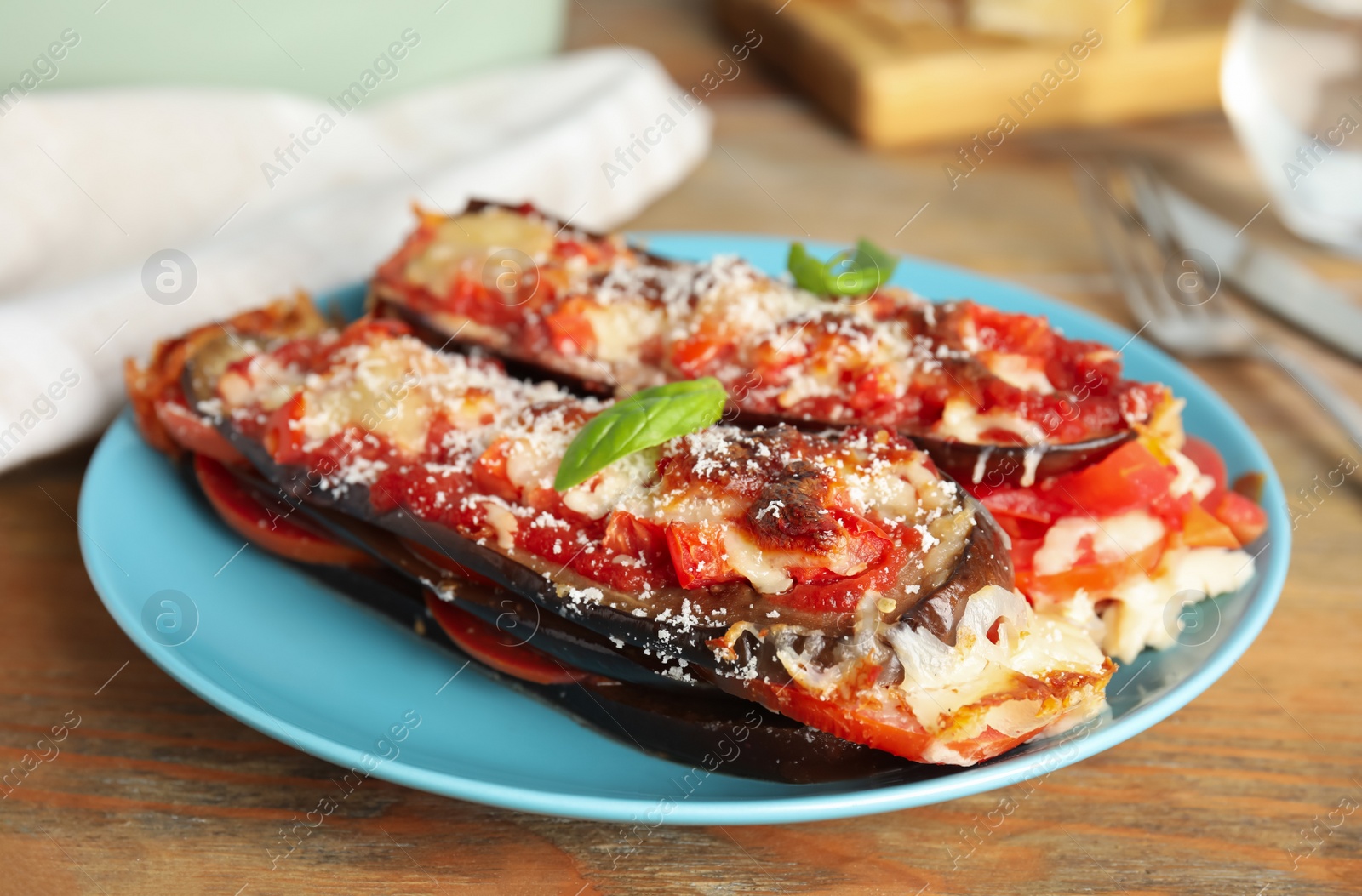 Photo of Baked eggplant with tomatoes, cheese and basil on wooden table, closeup