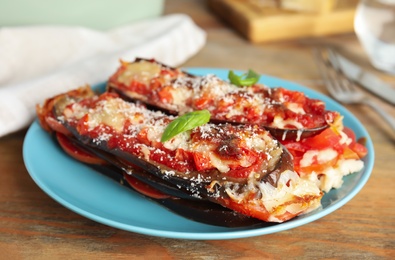 Baked eggplant with tomatoes, cheese and basil on wooden table, closeup