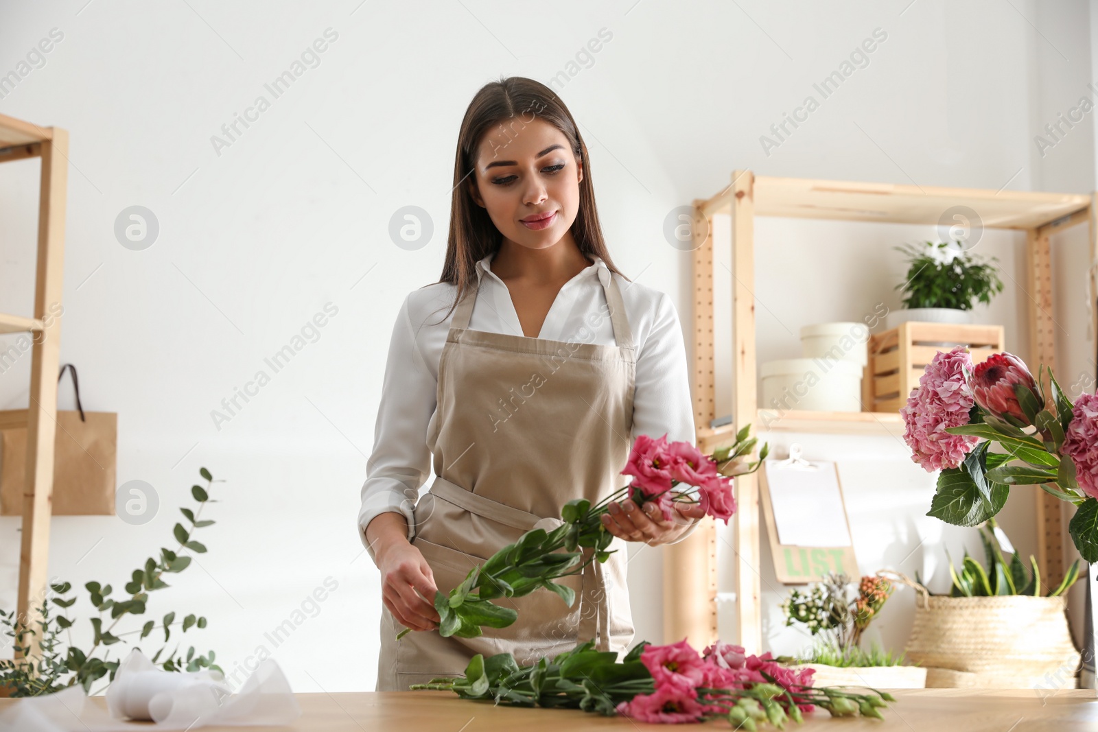 Photo of Florist making beautiful bouquet at table in workshop