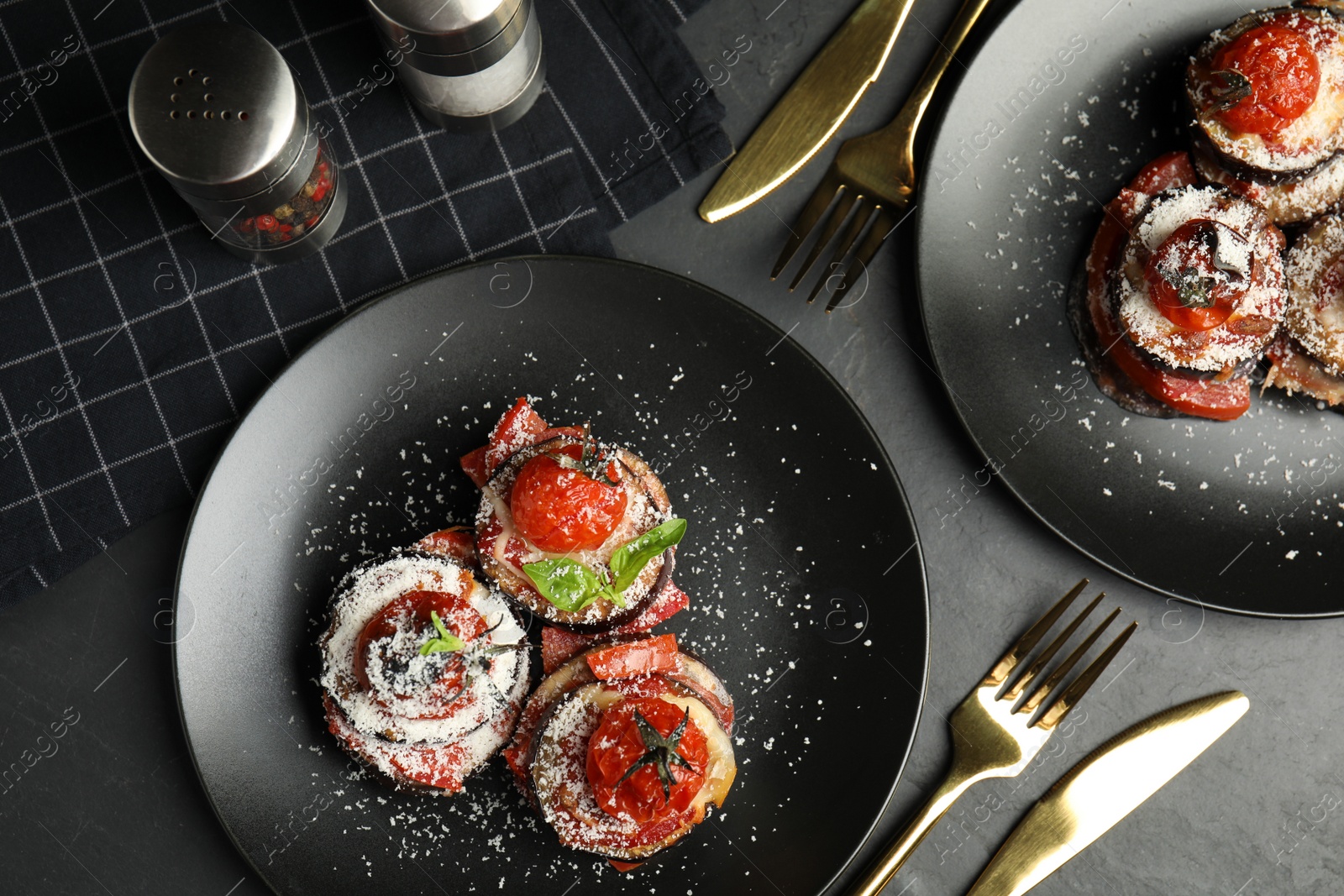 Photo of Baked eggplant with tomatoes, cheese and basil served on black table, flat lay