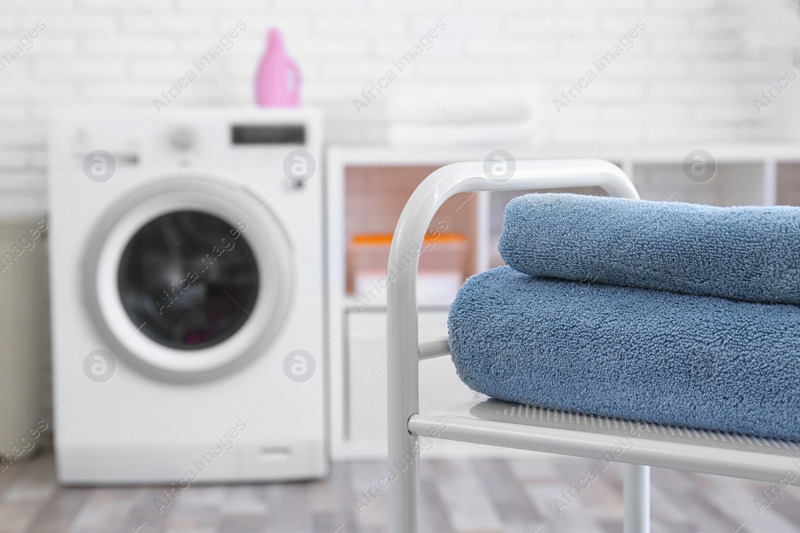 Photo of Folded clean terry towels on shelving unit in laundry room, space for text