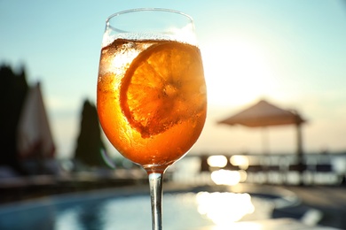 Photo of Glass of fresh summer cocktail at poolside outdoors at sunset, closeup
