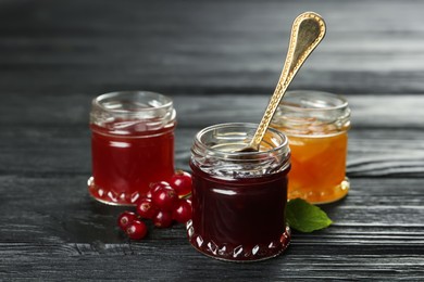 Photo of Jars of different jams on black wooden table