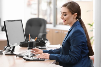 Young saleswoman sitting at table in car salon