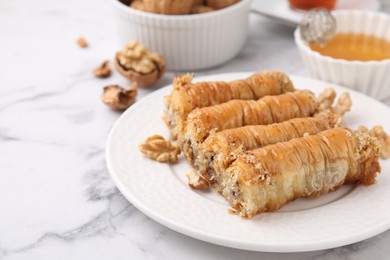 Photo of Eastern sweets. Pieces of tasty baklava on white marble table, closeup. Space for text