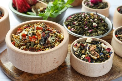 Photo of Many different herbal teas in bowls on table, closeup