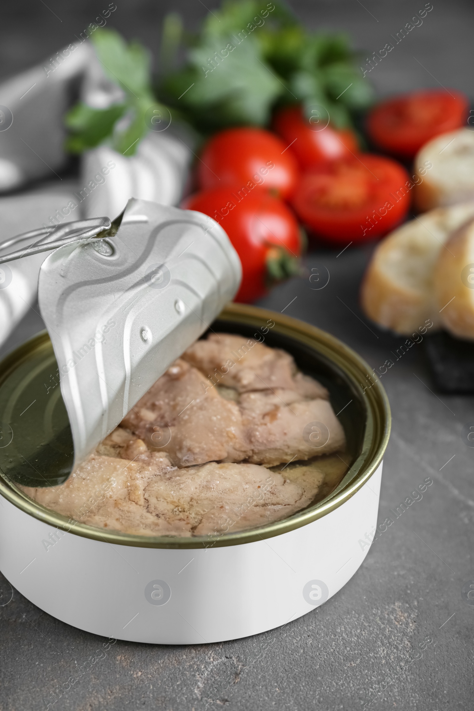 Photo of Open tin can of tasty cod liver on grey table, closeup