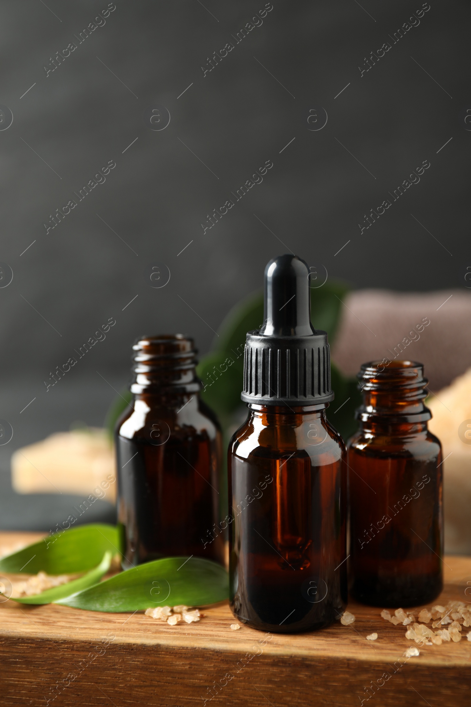 Photo of Composition with aroma oil bottles on wooden board, closeup