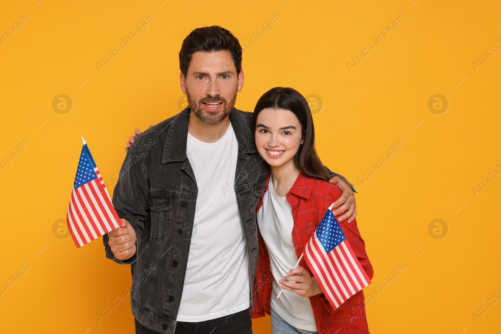 Photo of 4th of July - Independence Day of USA. Happy man and his daughter with American flags on yellow background