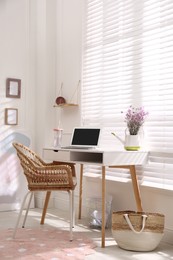 Photo of Comfortable workplace with modern laptop and flowers in room. Interior design