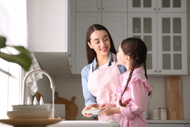 Photo of Mother and daughter washing dishes together in kitchen