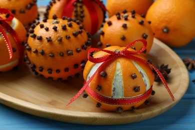 Pomander balls made of tangerines with cloves on light blue wooden table, closeup