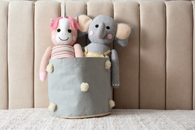 Funny toy unicorn and elephant in basket on bed. Decor for children's room interior