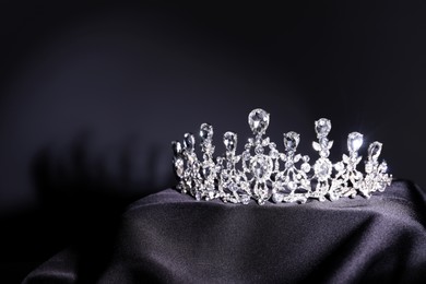 Photo of Beautiful silver tiara with diamonds on black cloth. Space for text