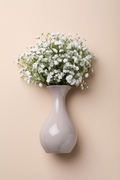 Photo of Bouquet of white gypsophila in ceramic vase on beige background, top view