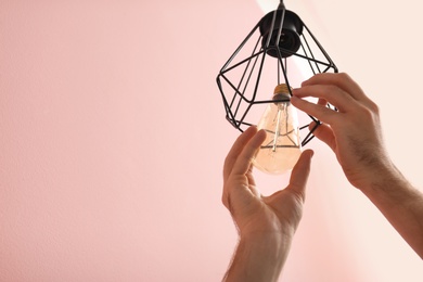 Man changing light bulb in lamp on color background. Space for text