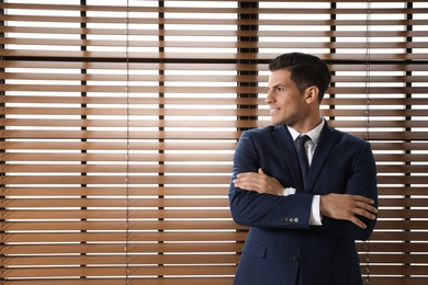 Portrait of confident businessman at window indoors. Space for text