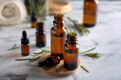 Bottles with rosemary essential oil on table