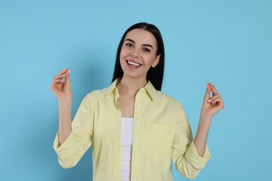 Photo of Young woman snapping fingers on light blue background