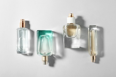 Bottles of perfume on light background, top view