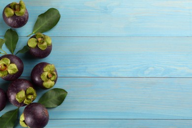 Photo of Fresh ripe mangosteen fruits on light blue wooden table, flat lay. Space for text