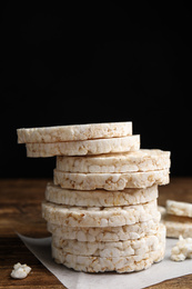 Photo of Stack of puffed rice cakes on wooden table against black background