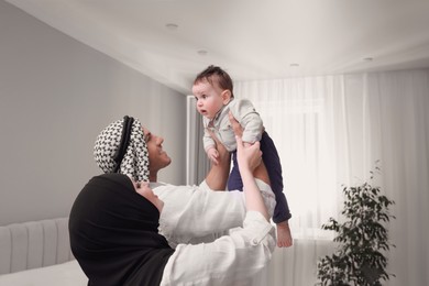 Photo of Happy Muslim family with little son in bedroom