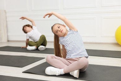 Group of children doing gymnastic exercises on mats indoors, selective focus