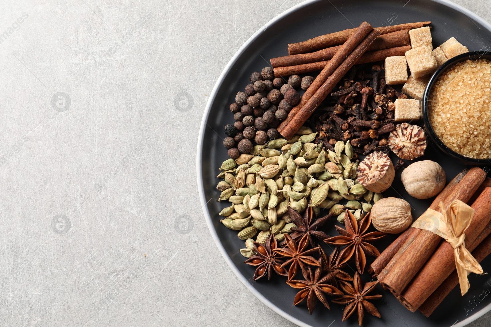 Photo of Plate with different aromatic spices on light textured table, top view. Space for text