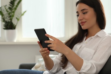 Young woman using e-book reader at home