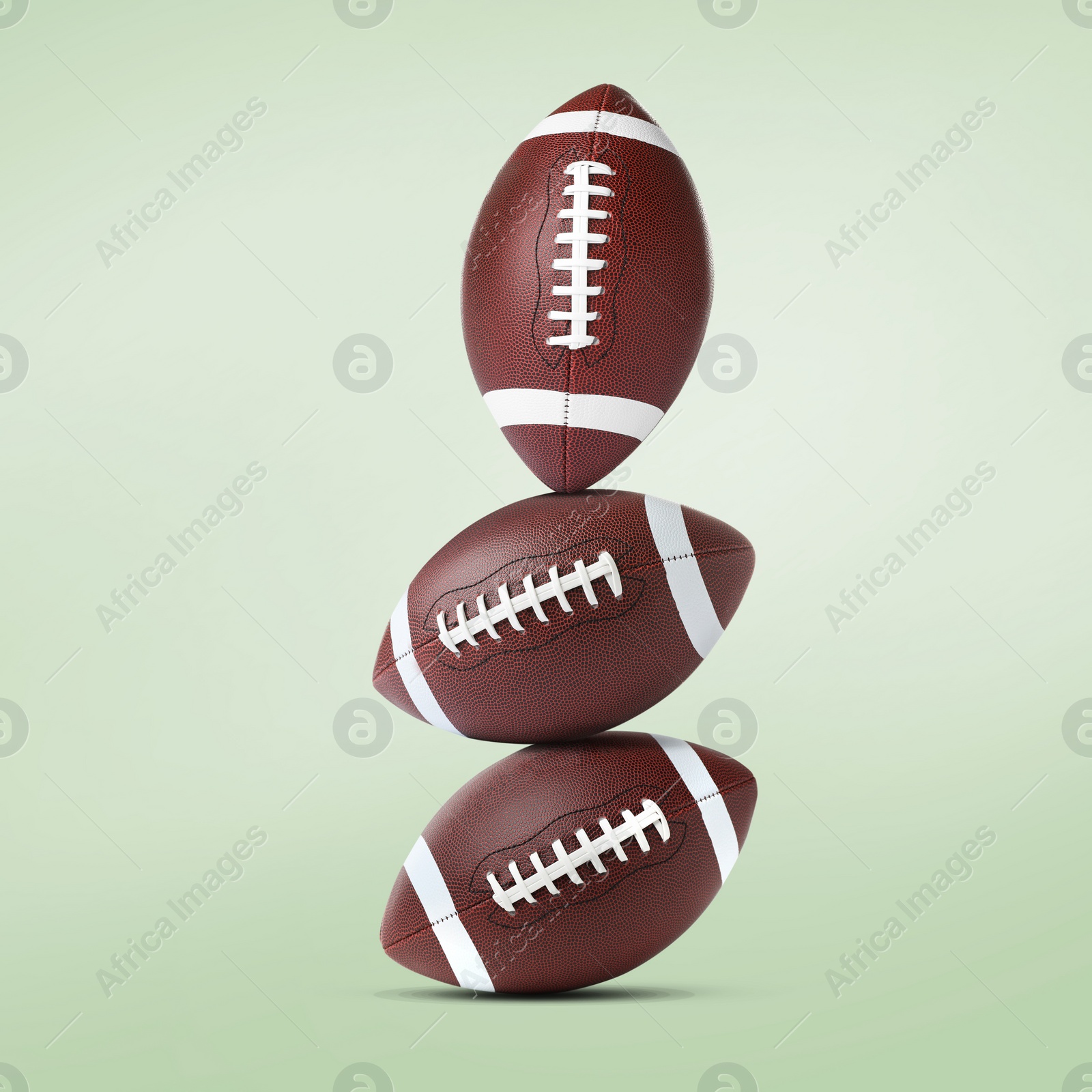 Image of Stack of American football balls on pale light green background