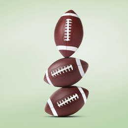 Image of Stack of American football balls on pale light green background