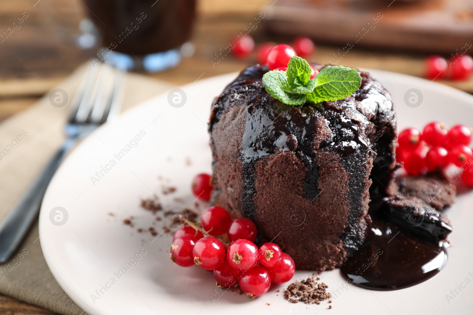 Photo of Delicious warm chocolate lava cake with mint and berries on plate, closeup