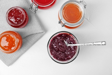 Photo of Jars with different sweet jam on white table