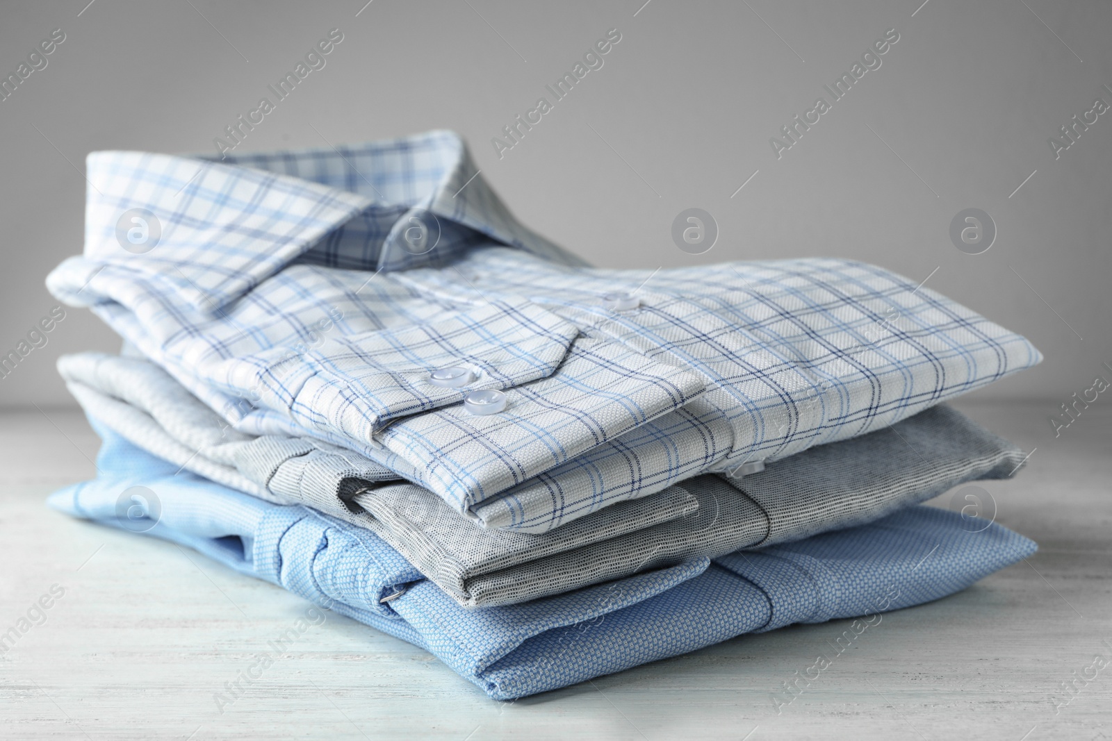 Photo of Stack of classic shirts on white wooden table