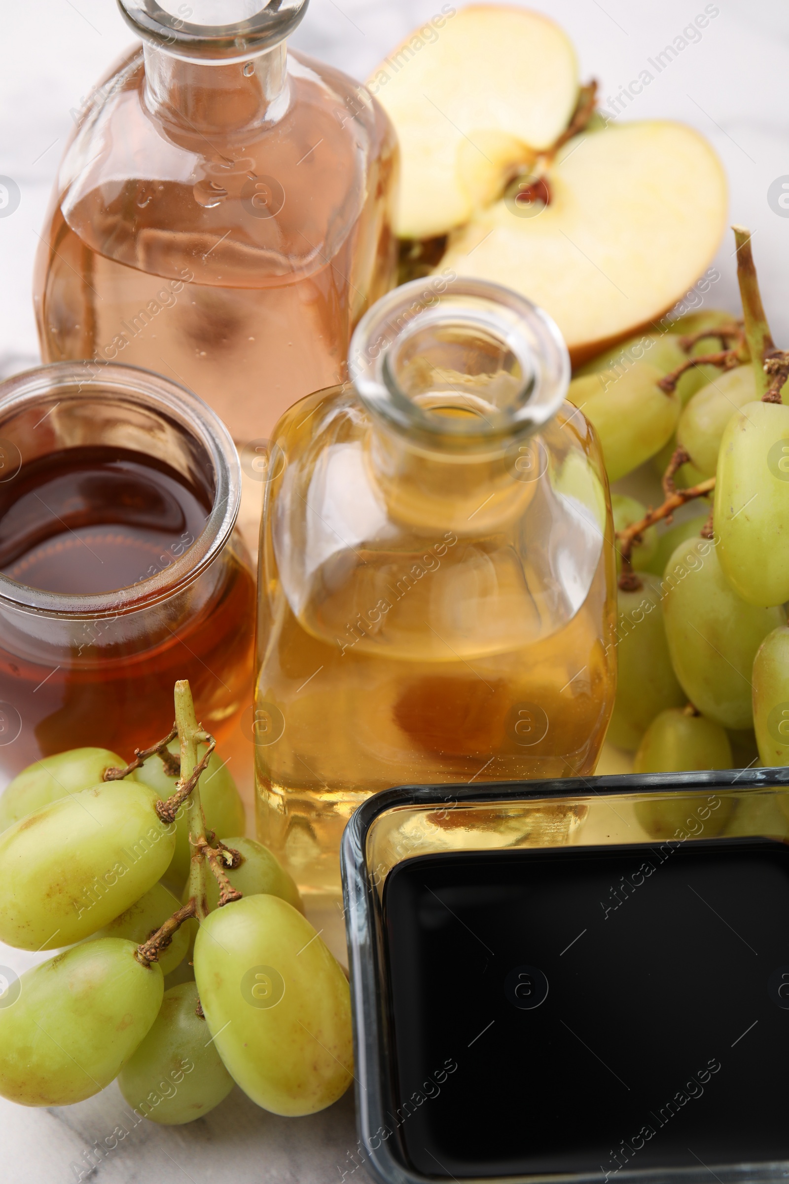 Photo of Different types of vinegar and ingredients on light table, closeup