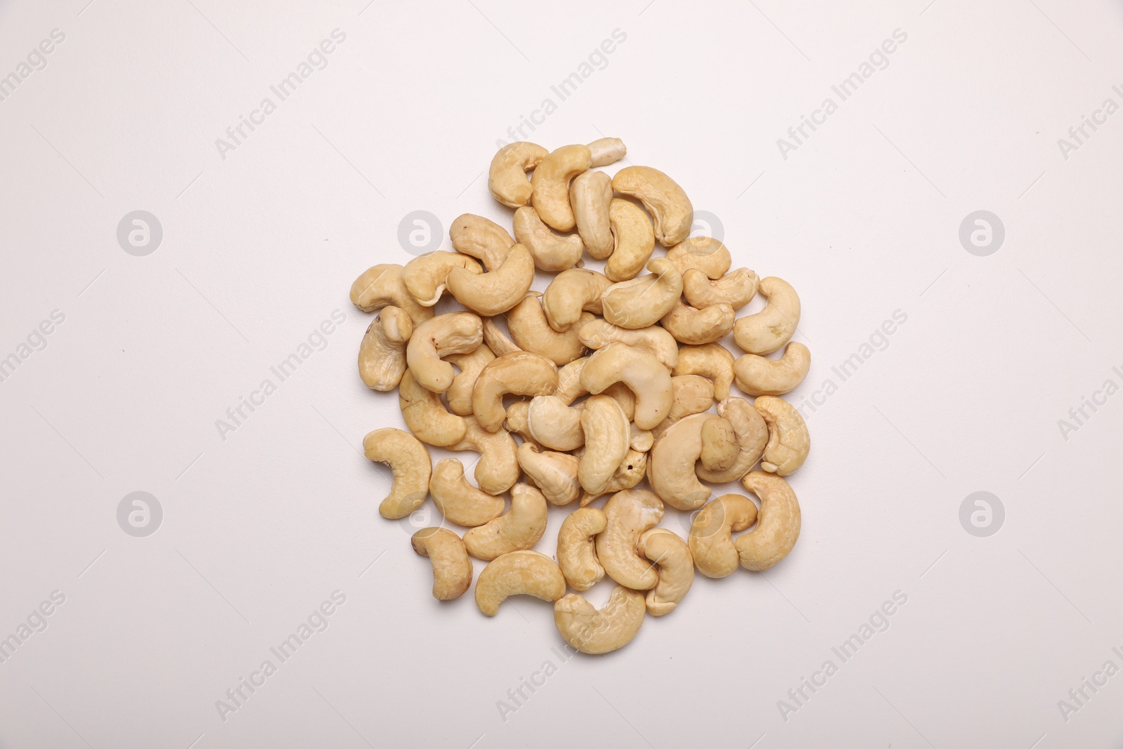 Photo of Pile of tasty cashew nuts on white background, top view