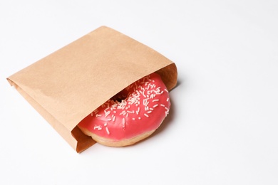 Paper bag with glazed doughnut on white background. Space for text