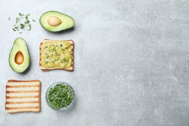 Photo of Delicious sandwich with guacamole and microgreens on grey table, flat lay. Space for text