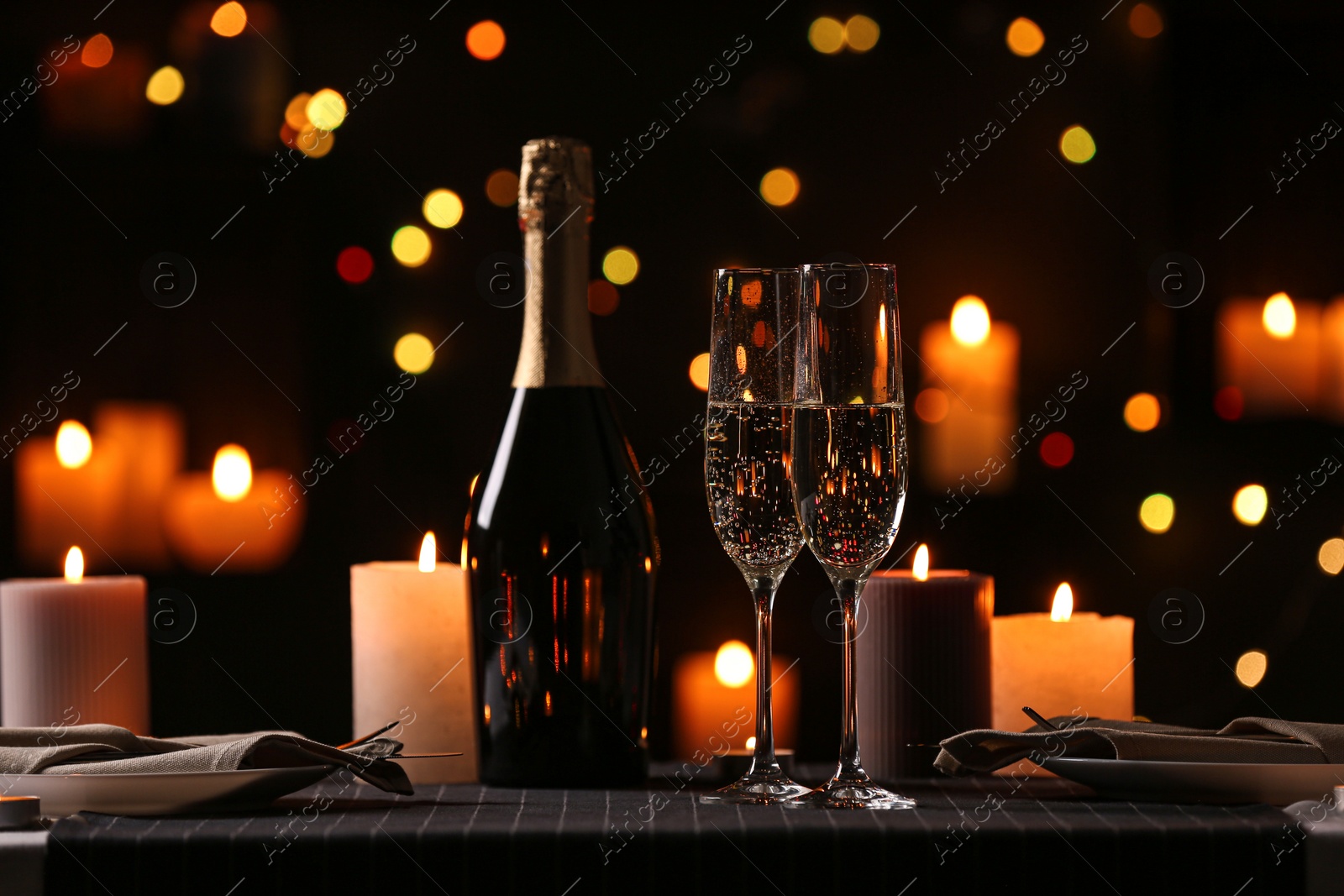 Photo of Romantic dinner table setting with burning candles and festive lights