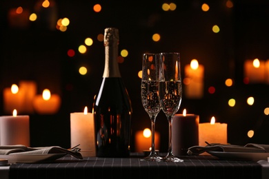 Photo of Romantic dinner table setting with burning candles and festive lights