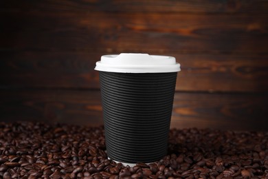 Photo of Coffee to go. Paper cup and roasted beans against wooden background