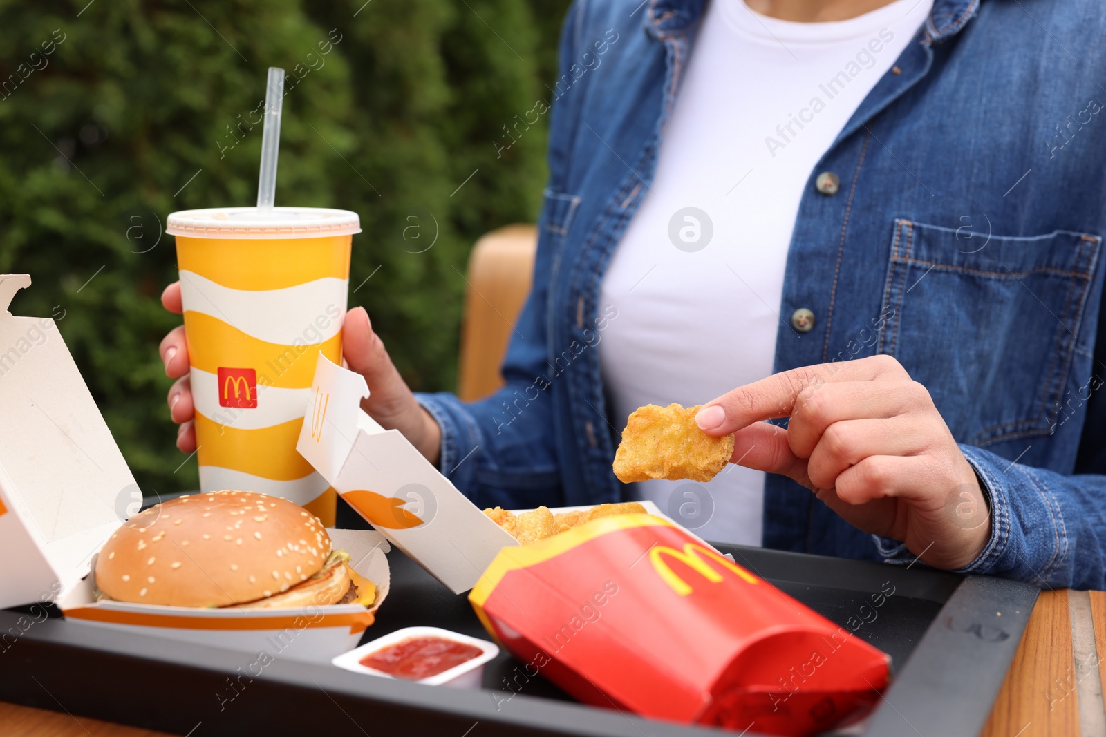 Photo of Lviv, Ukraine - October 9, 2023: Woman with McDonald's menu at table outdoors, closeup