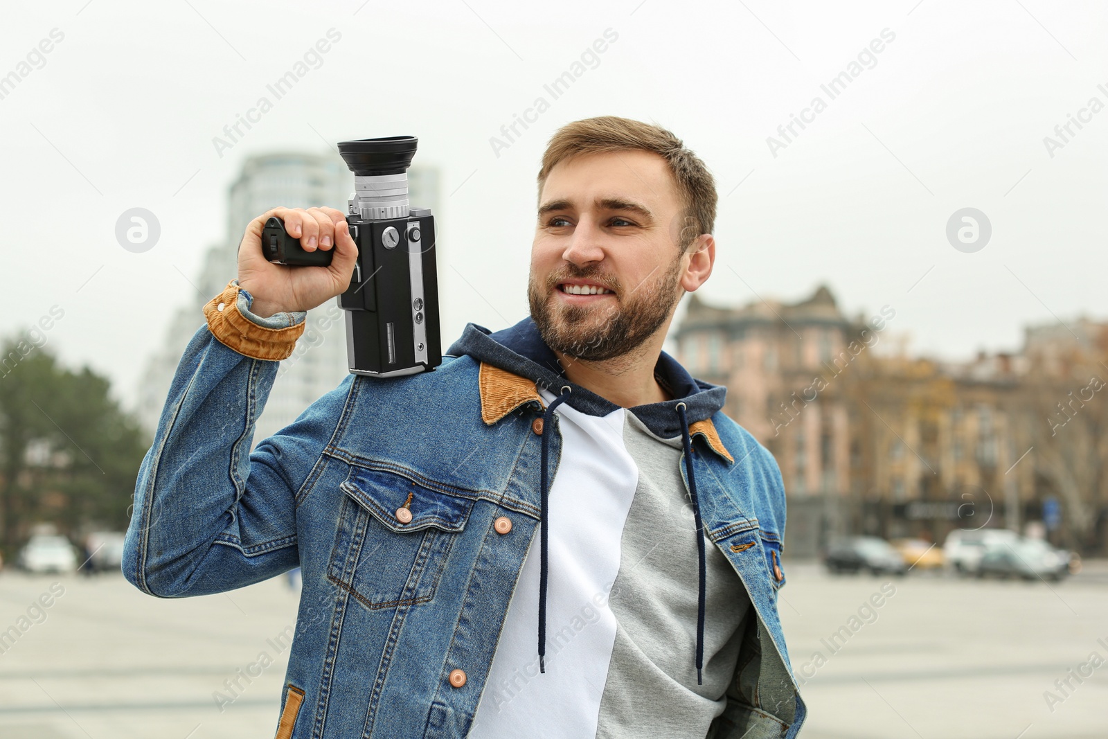 Photo of Young man with vintage video camera on city street